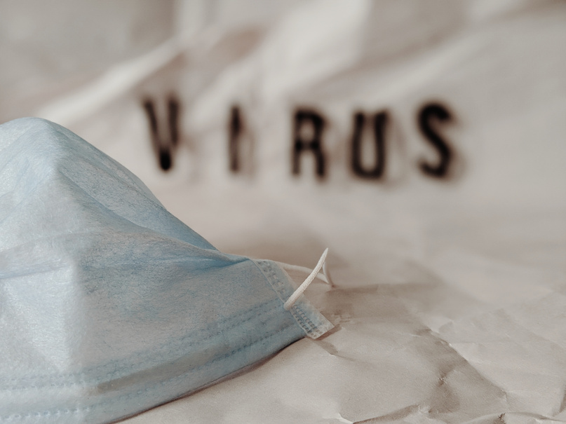 Blurred virus text and surgical mask on white background